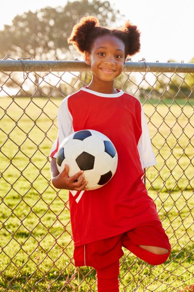 Pre teen black girl holding a soccer ball looking to camera